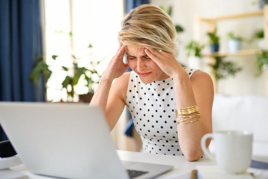 A woman sitting a desk is holding her head in frustration