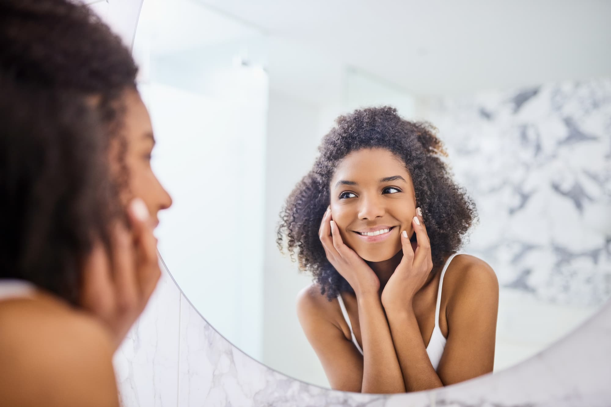 A woman admiring her reflection after skin rejuvenation in Denver