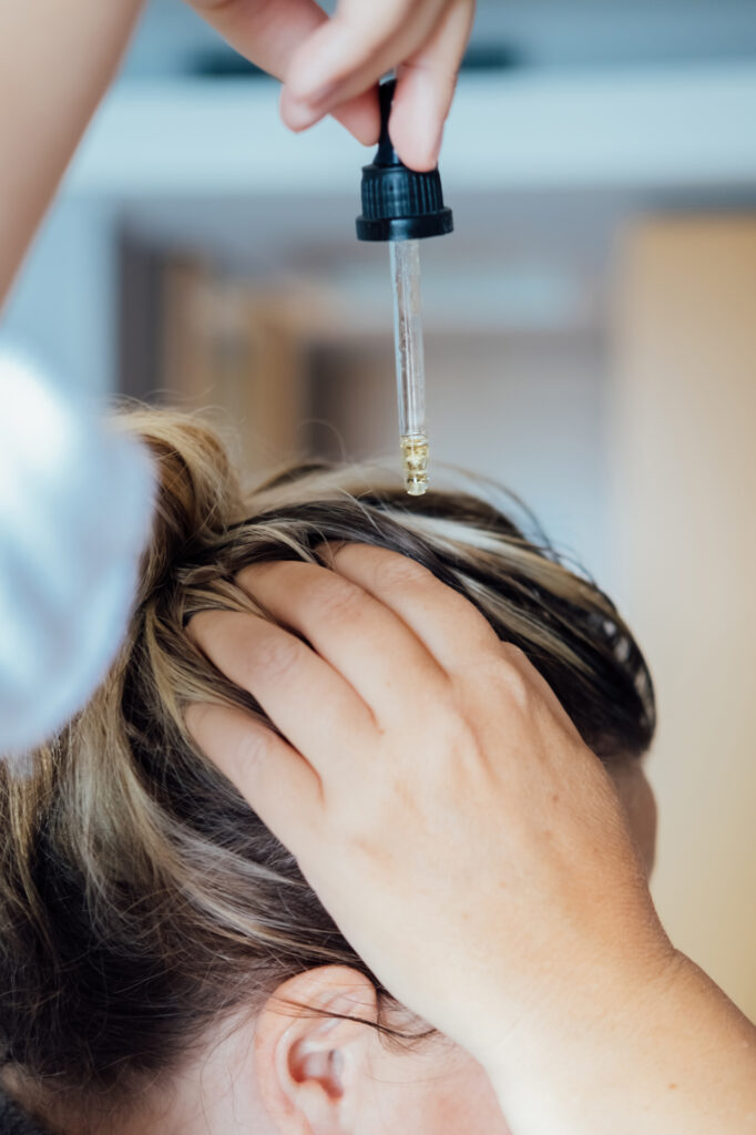 Woman applies oil to her scalp as a hair thinning solution in Greenwood Village