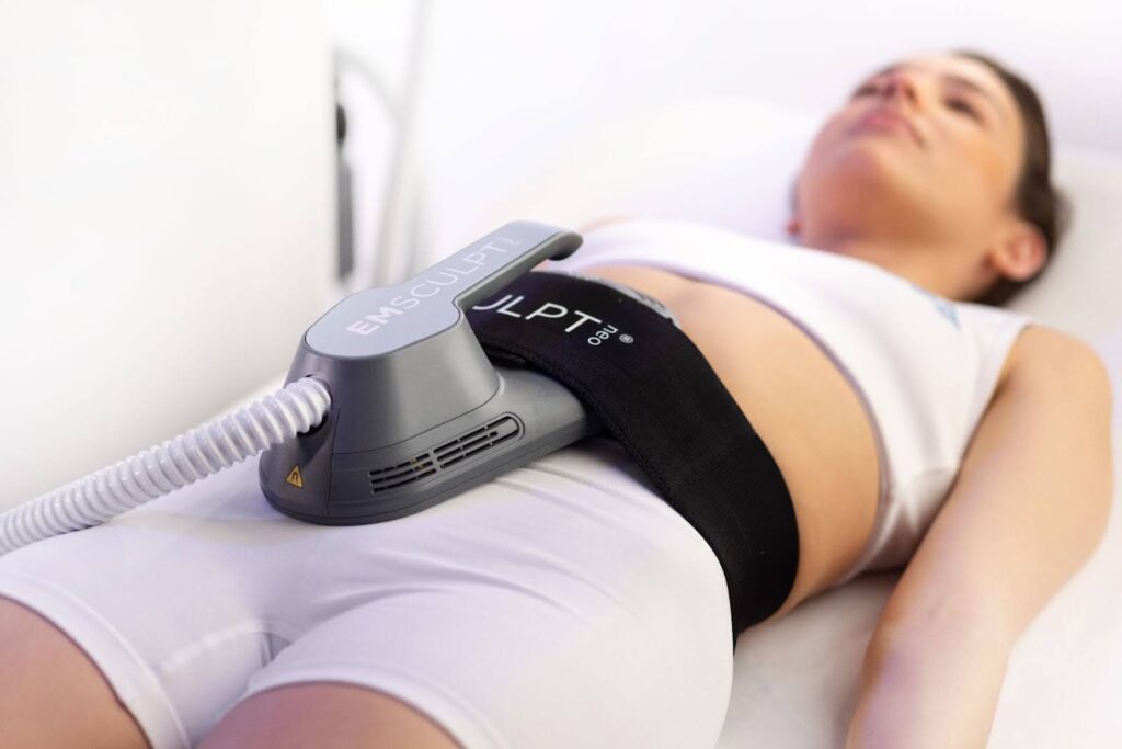 A woman lying down and undergoing an Emsculpt NEO treatment because it's one of the best ways to lose belly fat