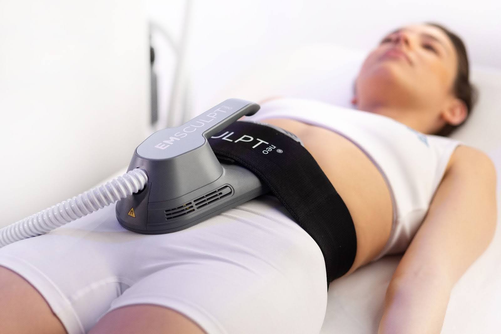 A woman lying down and undergoing an Emsculpt NEO treatment to boost Hormone Optimization in Denver