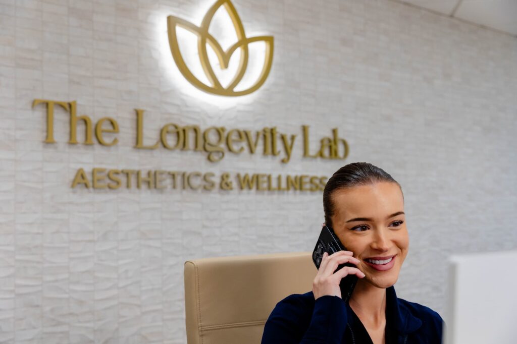 A provider at The Longevity Lab answering the phone at the front desk to discuss NAD+ therapy near Cherry Hills Village, CO