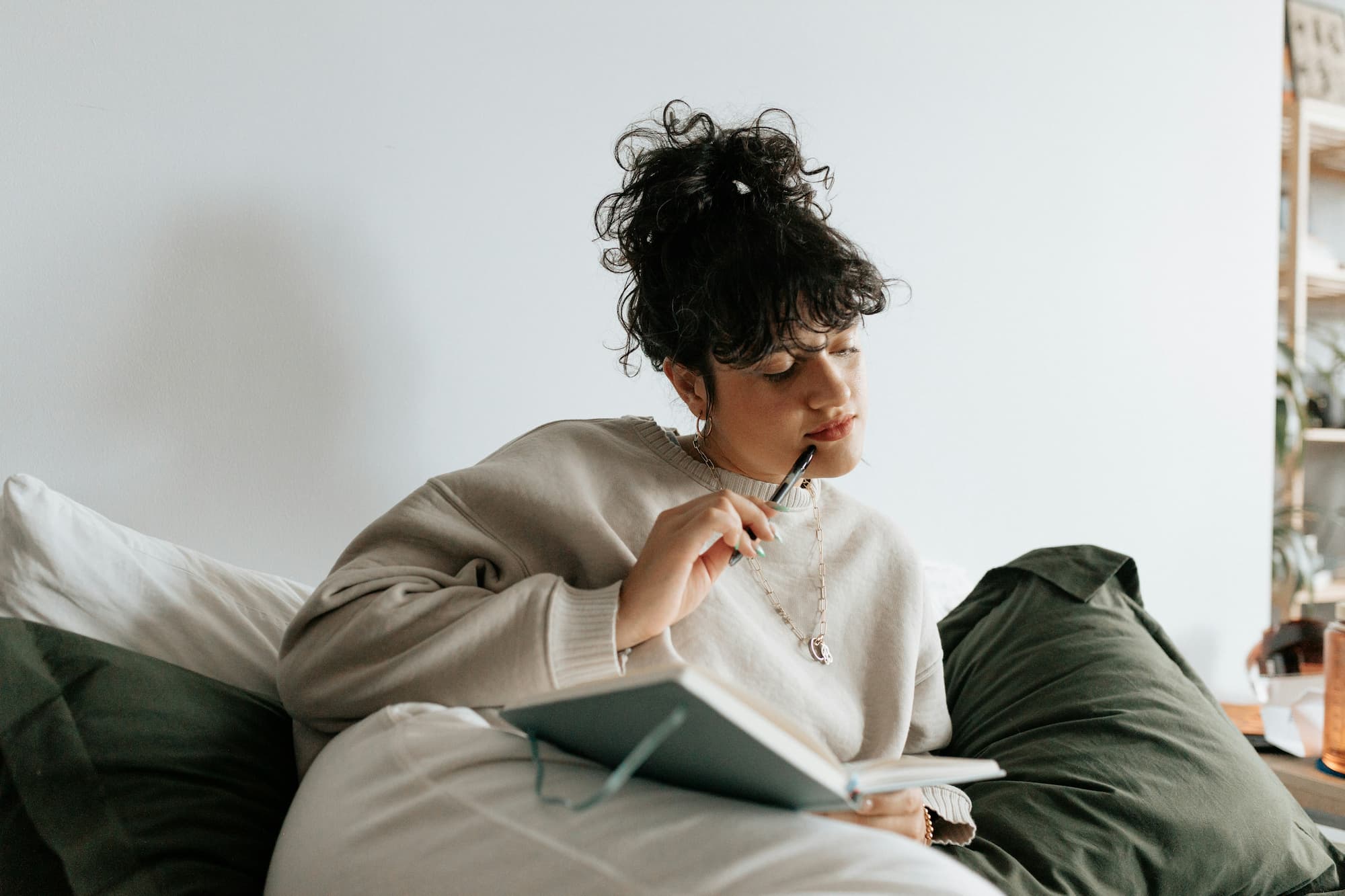 A contemplative woman holding a pen and journal to document her Personalized Wellness Plans 